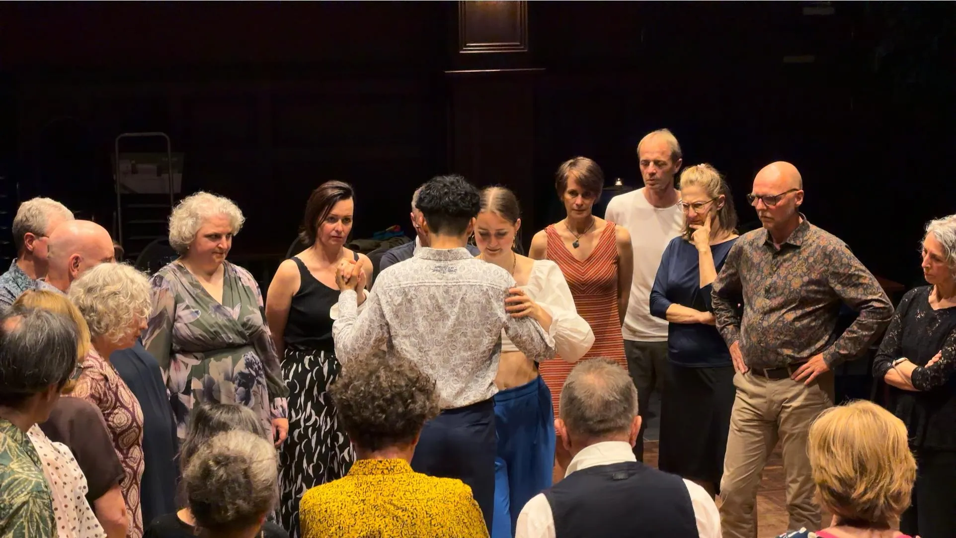 A tango class gathered around a dancing couple